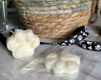 May include: Two white wax melts shaped like a paw print. The wax melts are packaged in a clear plastic bag.