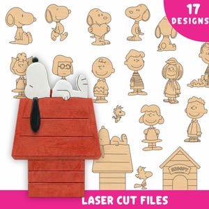 May include: Wooden laser cut files featuring 17 designs of cartoon characters, including Snoopy and his doghouse. The doghouse is red with a black roof. The text "17 DESIGNS" is in a pink circle, and "LASER CUT FILES" is at the bottom.