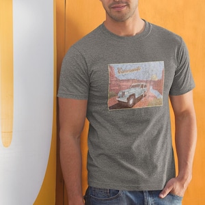 May include: A heather grey t-shirt with a vintage-style graphic of a blue jeep driving through a desert landscape. The graphic includes the text "Kommando".