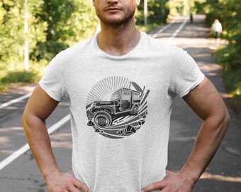 May include: A gray t-shirt with a black and white graphic of a jeep driving through a rocky landscape. The jeep has a sunburst behind it and the text "Rugged" on the side.