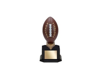 May include: A brown football trophy with the words "FANTASY FOOTBALL" printed on the football. The trophy has a black base with a gold-colored plate and a gold-colored stem.