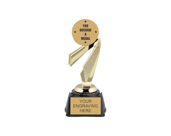 May include: Gold-colored trophy with a black base. The trophy features a round, gold-colored medal with the text "You Deserve A Medal" and a star design. The base has the text "Your Engraving Here".