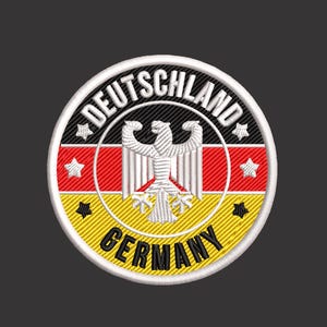 May include: A circular embroidered patch featuring the German flag colors of black, red, and gold. The center displays a white eagle emblem. The text DEUTSCHLAND is arched at the top, and GERMANY is arched at the bottom, with four white stars.
