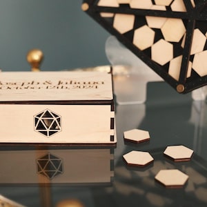 May include: A wooden box with a geometric design on the lid. The box is engraved with the text "Katelyn & Jalouri October 12th, 2021".