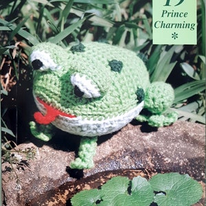 Peut inclure: Une grenouille en crochet verte avec une langue rouge, des yeux blancs et des pupilles noires. La grenouille est assise sur un rocher avec des feuilles vertes en arrière-plan. Le texte "19 Prince Charming *" est dans le coin supérieur droit de l'image.