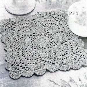 Puede incluir: Un mantel individual cuadrado de ganchillo gris con un patrón delicado e intrincado. El mantel individual está hecho con un hilo fino y tiene un borde festoneado. El texto "COTTAGE PUPPY" es visible en la parte superior central de la imagen.