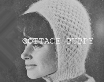 May include: A close-up of a woman wearing a white knitted hat with a hood. The hat has a textured pattern and the text "COTTAGE PUPPY" is printed on the front.