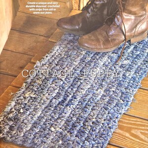 May include: A blue denim doormat crocheted from strips of old jeans. The doormat is on a wooden floor and has the text "COTTAGE PUPPY" printed on it.