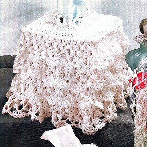 May include: White crocheted tissue box cover with a delicate lace pattern. The cover is round and has a ruffled edge.