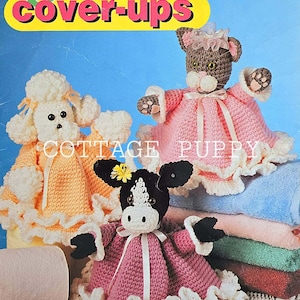 May include: Crochet Critter Cover-Ups pattern booklet featuring a poodle, cat, and cow toilet paper cover designs. The cover features the title "Crochet Critter Cover-Ups" in yellow and green letters.