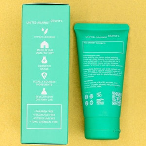 Pu&ograve; includere: Un tubo verde di crema per le mani con le parole "United Against Gravity" sul davanti. Il retro del tubo elenca gli ingredienti e le istruzioni per l'uso. Il tubo &egrave; su una superficie gialla.