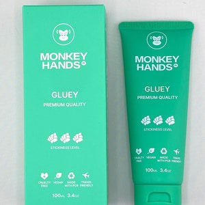 May include: A green tube of hand cream with the words "MONKEY HANDS" and "GLUEY PREMIUM QUALITY" printed on the front. The tube is 100 ml and contains cruelty-free, vegan, and travel-friendly hand cream.
