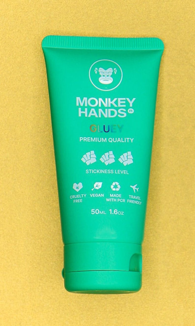 Pu&ograve; includere: Un tubo color turchese di crema per le mani con le parole "MONKEY HANDS GLUEY" stampate sul davanti. Il tubo &egrave; etichettato "PREMIUM QUALITY" e ha un adesivo con un'immagine di una scimmia. Il tubo &egrave; da 50 ml o 1,6 oz.