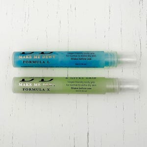 May include: Two small blue and green bottles with white labels. The labels read "Make Me Dewy Formula L" and "Make Me Dewy Formula X & Gives Grip". Both bottles are labeled as vegan-friendly body grip for normal to extra dry skin. The bottles are 9 ml (0.34 oz).