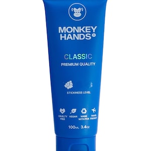 May include: Blue tube of Monkey Hands Classic hand cream with a monkey logo and the text "STICKINESS LEVEL" and "CRUELTY FREE, VEGAN, MADE WITH PCR, TRAVEL FRIENDLY". The tube is 100ml or 3.4oz.