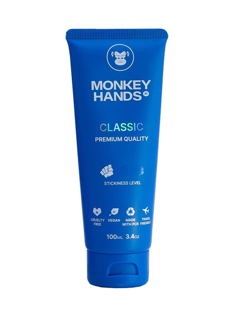 May include: Blue tube of Monkey Hands Classic hand cream with a monkey logo and the text "STICKINESS LEVEL" and "CRUELTY FREE, VEGAN, MADE WITH PCR, TRAVEL FRIENDLY". The tube is 100ml or 3.4oz.