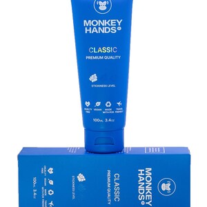 May include: A blue tube of Monkey Hands Classic Premium Quality hand cream with a monkey logo. The tube is 100 ml or 3.4 oz. The tube is sitting on top of a blue box with the same logo and text.