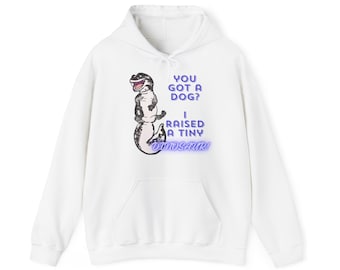 Puede incluir: Sudadera con capucha blanca con un gráfico de un gecko y el texto "You got a dog? I raised a tiny dinosaur!"