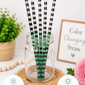 May include: Five reusable drinking straws with a black and white horizontal striped pattern that transitions to a green and black striped pattern when cold. The straws are displayed inside a clear glass jar, with text indicating they are cold activated.