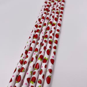 Op de afbeelding: Een set witte potloden met een patroon van rode aardbeien en roze harten.