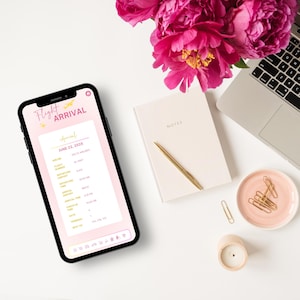 May include: A pink and white smartphone displaying a flight arrival list for June 22, 2018. The list includes flight numbers, airlines, and arrival times. The phone is on a white surface with a pink notebook, a gold pen, a pink dish with gold paper clips, and a white candle.
