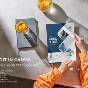 May include: A person holding an "Annual Report" with a blue and white cover. The report has the year 2024 on it. A glass of orange-infused water sits on a gray notebook. The text "EDIT IN CANVA" is visible.