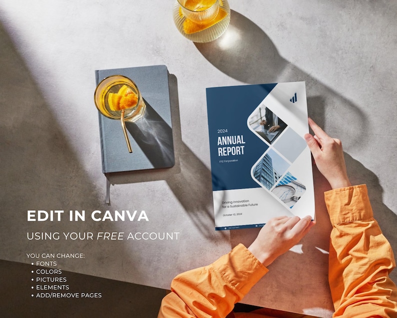 May include: A person holding an "Annual Report" with a blue and white cover. The report has the year 2024 on it. A glass of orange-infused water sits on a gray notebook. The text "EDIT IN CANVA" is visible.