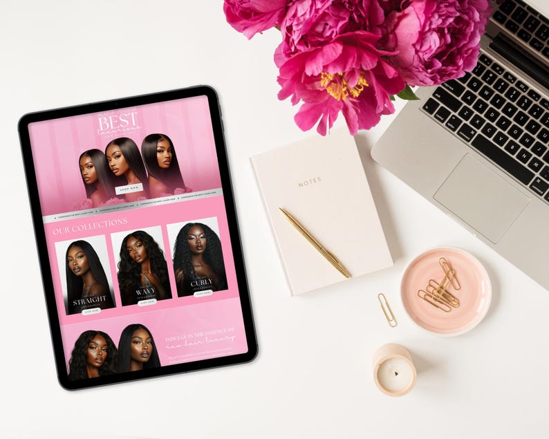 May include: A digital tablet displays a website with images of hair extensions. The tablet is surrounded by a laptop, notebook, pen, candle, and a small dish with paper clips. A bouquet of pink flowers sits above the tablet.
