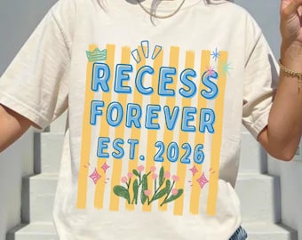 Op de afbeelding: Ivoor kleurig t-shirt met de tekst "RECESS FOREVER EST. 2026" in een blauw en geel ontwerp. De afbeelding bevat een kroon, sterren en cactussen. Het shirt wordt gecombineerd met een blauw-wit gestreepte broek.
