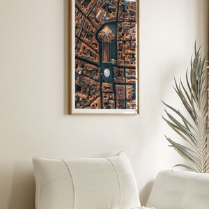 May include: An aerial photograph of a city with a large, domed building in the center. The buildings are all brown and the streets are narrow. The photo is framed in a wooden frame.