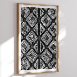 May include: Monochrome aerial photograph of a city grid, framed in light wood. The image presents a repeating pattern of buildings and streets, forming a geometric design. The photograph is a high-angle shot, providing a unique perspective of the urban landscape.