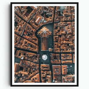 May include: An aerial view of a city with a large, domed building in the center. The building is surrounded by smaller buildings with red tile roofs. The streets are narrow and winding.