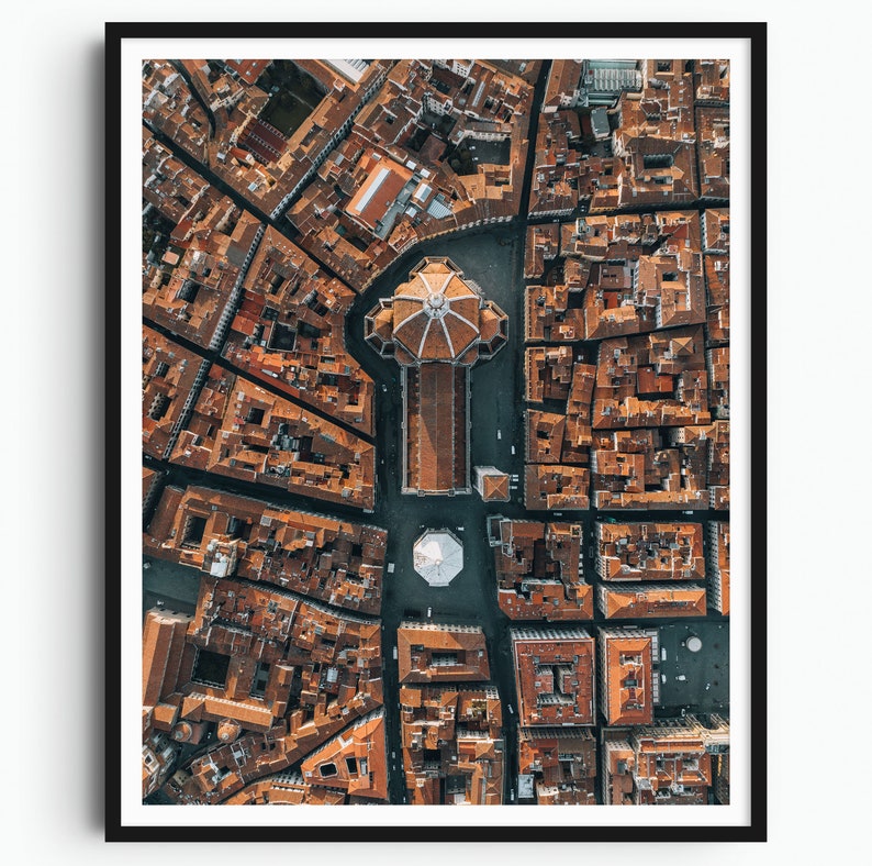 May include: An aerial view of a city with a large, domed building in the center. The building is surrounded by smaller buildings with red tile roofs. The streets are narrow and winding.