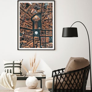 May include: An aerial photograph of a city with a large, domed building in the center. The buildings are all made of brick and have terracotta roofs. The streets are narrow and winding.