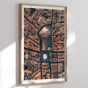 May include: An aerial photograph of a city with a large, domed building in the center. The building is surrounded by smaller buildings and streets. The photo is taken from a high angle, giving a bird's-eye view of the city.