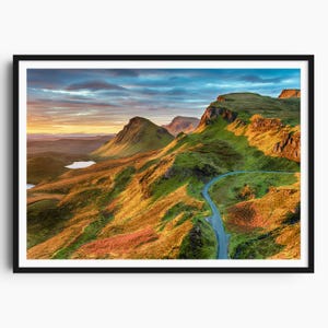 May include: A framed print of a scenic landscape, showing a road snaking through green hills under a colourful sky. The image showcases the natural beauty of the terrain, with a small loch visible. The artwork is presented in a black frame.