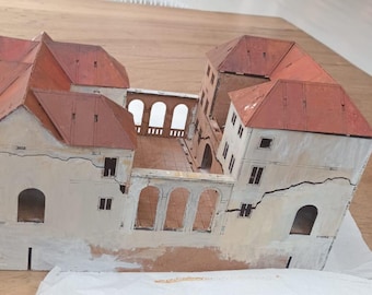 May include: A model of a white building with red roofs and a courtyard in the center. The building has many windows and is made of cardboard.