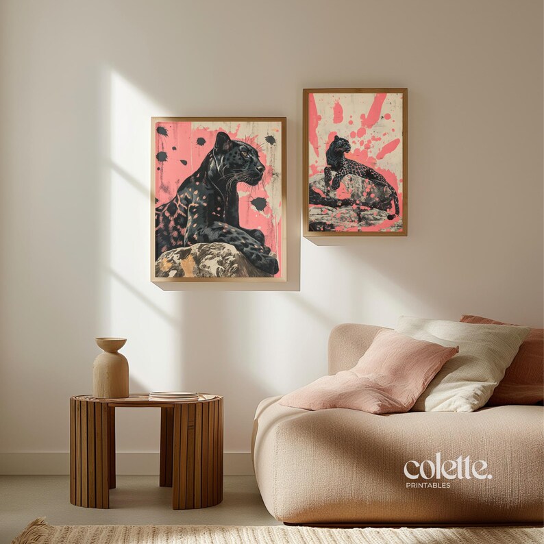 May include: Two framed prints of black leopards on a pink background. The print on the left shows a leopard lying down, while the print on the right shows a leopard sitting up. Both prints have a white border.