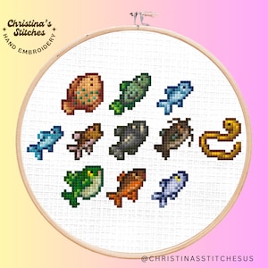 May include: Cross stitch embroidery hoop featuring a design of various fish and a snake. The fish are in different colours and styles, including a catfish, a pufferfish, and a bass. The snake is yellow and is curled up in the corner of the hoop. The hoop is made of wood and has a white fabric background.