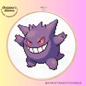 May include: A purple and white cross-stitch embroidery of a cartoon ghost-like Pokemon character with a menacing grin. The character is named Gengar and is from the Pokemon franchise. The embroidery is framed in a wooden hoop.