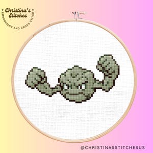 May include: Cross stitch pattern of a green and gray Pokemon character with its arms flexed, showing its muscles. The character is on a white background.
