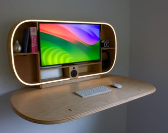 May include: A modern, wall-mounted desk with a built-in monitor and shelves. The desk is made of light-colored wood and features a curved design with a glowing light strip. A keyboard and mouse sit on the desk surface. The monitor displays a colorful abstract image.