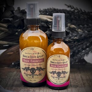 Peut inclure: Deux flacons en verre ambr&eacute; avec des vaporisateurs noirs et des &eacute;tiquettes. Les &eacute;tiquettes sont de couleur cr&egrave;me avec du texte noir qui indique "HAND CRAFTED THIRD STATE HOME & LINEN SPRAY DARK CARNIVAL Spin Sugar | Tobacco | Wood Nevermore Crafting Company" et la taille du flacon en onces. Le plus petit flacon est de 2 oz et le plus grand de 4 oz. Les flacons sont sur une surface brun fonc&eacute;.
