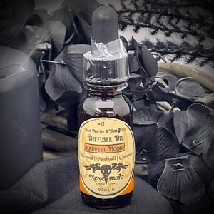 May include: A small, dark glass bottle of Harvest Moon diffuser oil with a black dropper. The label reads "Harvest Moon" with the ingredients listed below. The bottle is 0.5 oz.