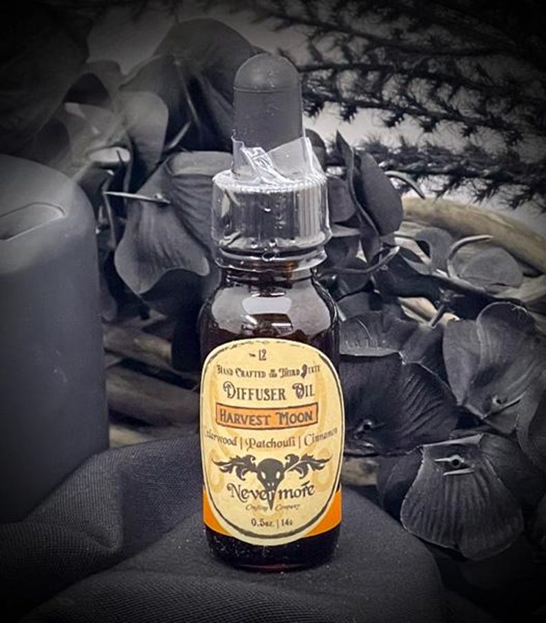 May include: A small, dark glass bottle of Harvest Moon diffuser oil with a black dropper. The label reads "Harvest Moon" with the ingredients listed below. The bottle is 0.5 oz.