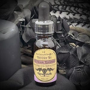 May include: A small, brown glass bottle of Victorian Mourning diffuser oil with a black dropper. The label features the text "Victorian Mourning" and "Nevermore". The bottle is 0.5 oz. in size and is surrounded by dark, gothic-themed decor.