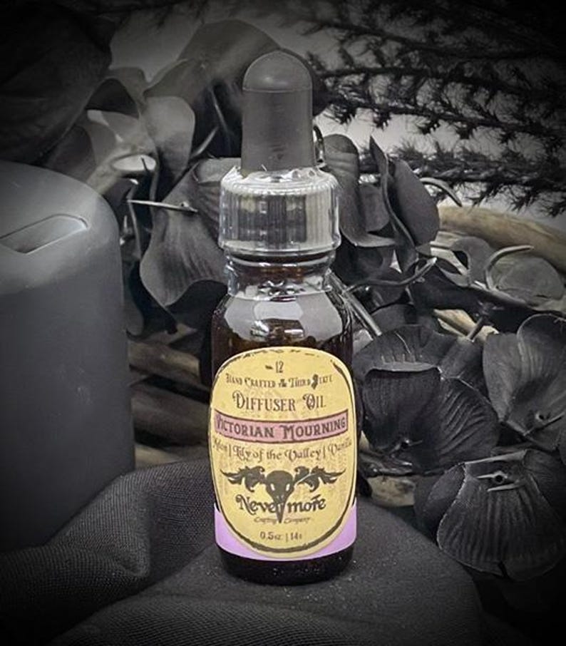 May include: A small, brown glass bottle of Victorian Mourning diffuser oil with a black dropper. The label features the text "Victorian Mourning" and "Nevermore". The bottle is 0.5 oz. in size and is surrounded by dark, gothic-themed decor.