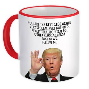 May include: White ceramic mug with a red handle and rim. The mug features a picture of a man and text that reads "YOU ARE THE BEST GEOCACHER...FAKE NEWS. BELIEVE ME."