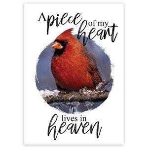 May include: A print featuring a vibrant red cardinal perched on a snow-covered branch, set against a soft blue background. The text "A piece of my heart lives in heaven" is written in elegant script above and below the bird.