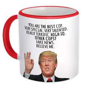 May include: White coffee mug with a red rim. The mug has a black and white image of Donald Trump with the text "YOU ARE THE BEST COP. VERY SPECIAL. VERY TALENTED. REALLY TERRIFIC. HIGH IQ. OTHER COPS? FAKE NEWS. BELIEVE ME."